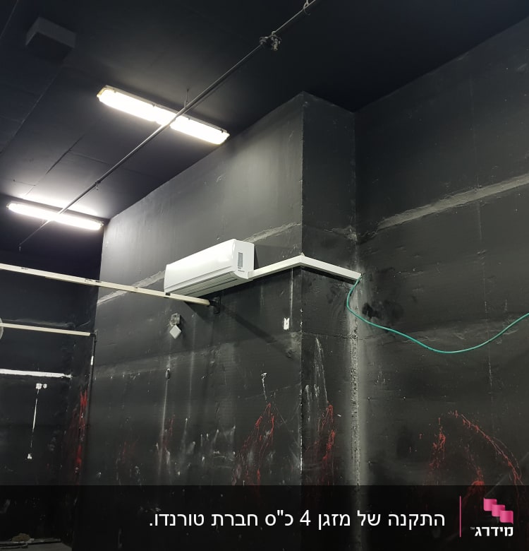 מזגן מותקן על קיר שחור עם חוט ירוק